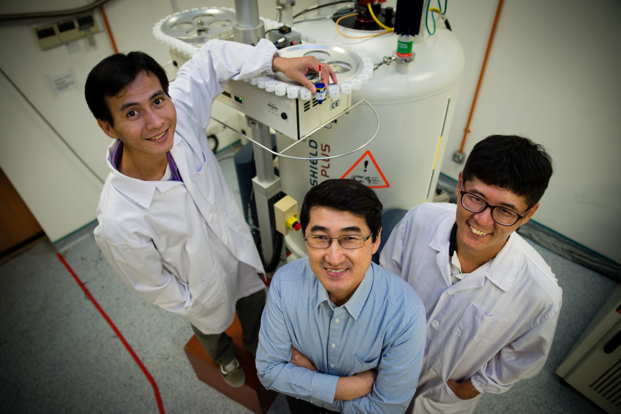 NTU Assoc Prof Yoon Ho Sup (centre), Dr Shin Joon (right) and Mr Nguyen Quoc Toan (left) in front of the NMR spectroscopy machine used in their experiments.